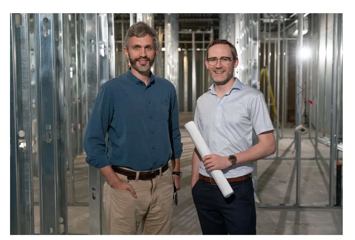 Dr. Walker and Dr. Laschuck standing in a building under construction